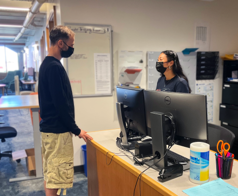 A student talking to a student-staff member at the testing center front desk